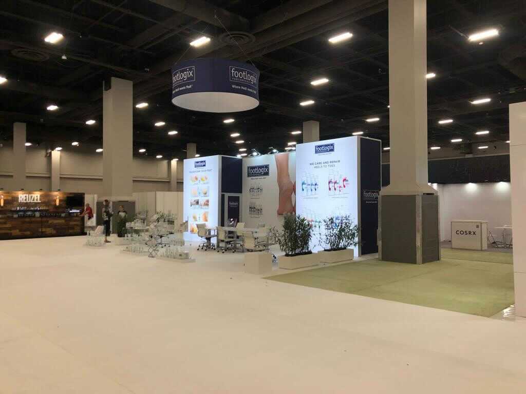 Footlogix completed booth: a circular hanging sign above product shelves, posters and a seating area