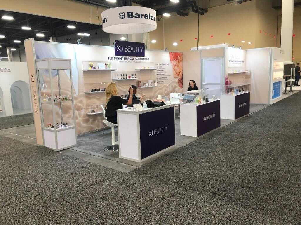 XJ Beauty completed booth: product shelving and graphic panels around a central reception counter