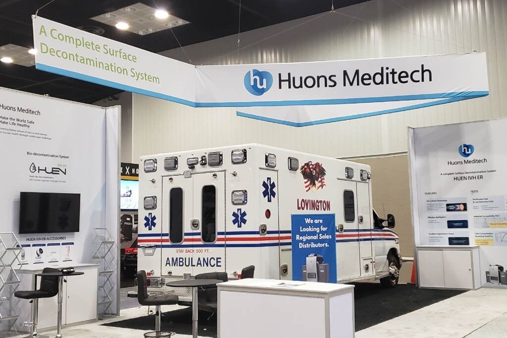 Huons Medicare completed booth: an overhead frame around a vehicle display and product-information panels