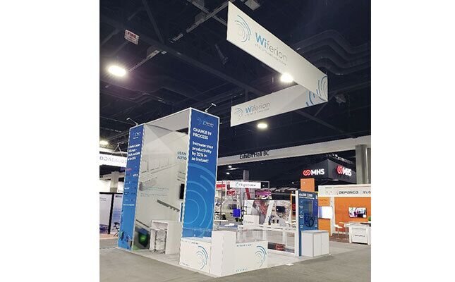 Wiferion completed booth: an angular hanging sign above a tall central tower and product counters