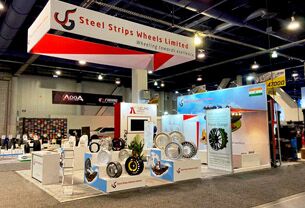 Steel Strips Wheels Limited completed booth: a long hanging sign above wall-mounted wheel displays and counters