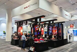 NKT Photonics completed booth: a broad canopy over graphic walls, product displays and a seating area