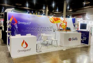 Firefly completed booth: a sweeping graphic back wall behind an angular counter and meeting tables