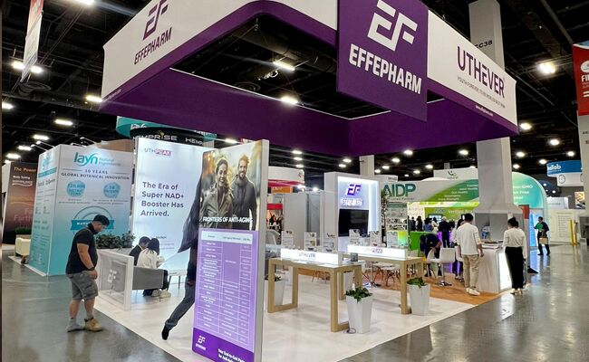 Effepharm completed booth: a suspended box sign over a central tower and freestanding product stations
