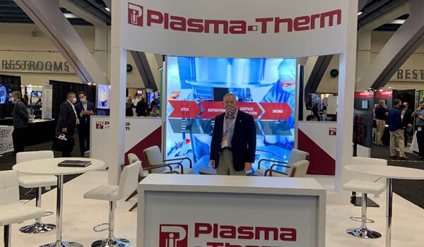 Plasma Therm completed booth: a framed display tower with a central screen and reception counter
