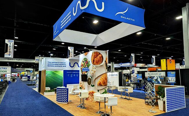 Galactic completed booth: a rectangular hanging sign above food-product graphics and a meeting area