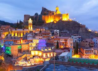 Colorful hillside buildings beneath an illuminated fortress