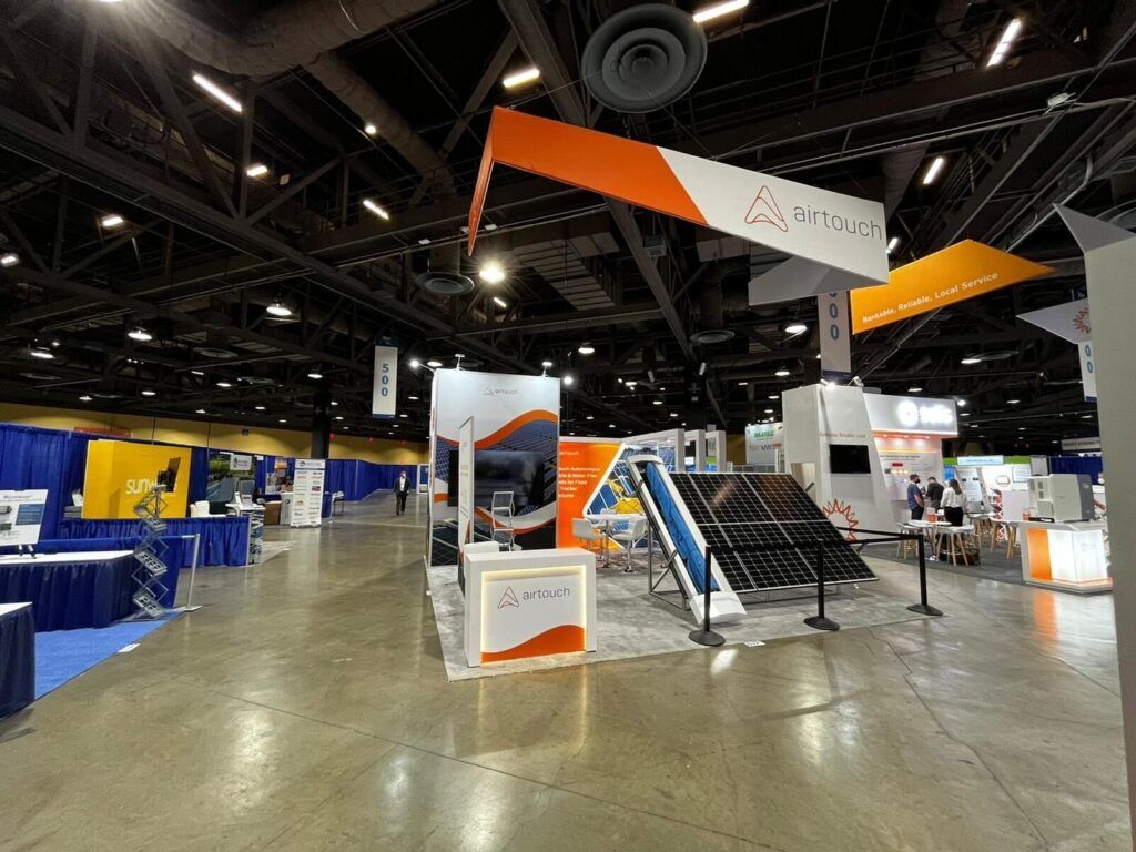 Airtouch Solar completed booth: an angular hanging sign above a tilted solar-panel demonstration