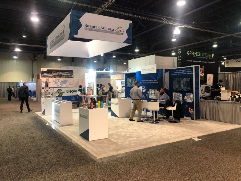 Shemesh Automation completed booth: a rectangular hanging sign above information panels and a reception counter