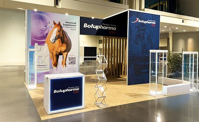 Botupharma completed booth: a tall graphic wall beside a reception counter and stools