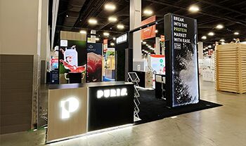 Puris completed booth: a rectangular overhead frame above product shelving and a reception desk