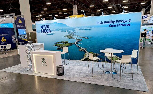 G.C. Rieber completed booth: a coastal graphic back wall behind a reception counter and café table