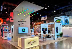 Variowell completed booth: an angular canopy with patterned graphics above a screen and reception counter