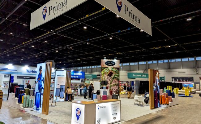 Prima USA completed booth: a rectangular hanging sign above freestanding product displays and counters