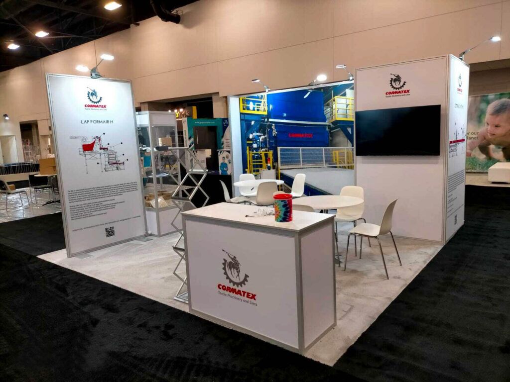 CORMATEX completed booth: a compact graphic back wall behind a reception counter and meeting table