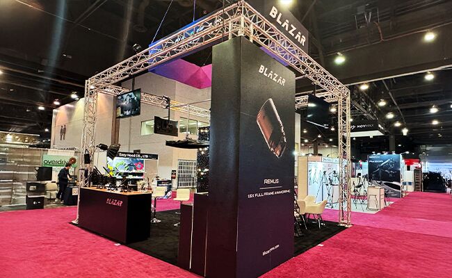 Blazar Lens completed booth: a tall central display tower beneath a suspended rectangular sign