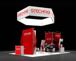 Angled view of a Gtechniq booth showing red display towers, reception counters and a seating area.