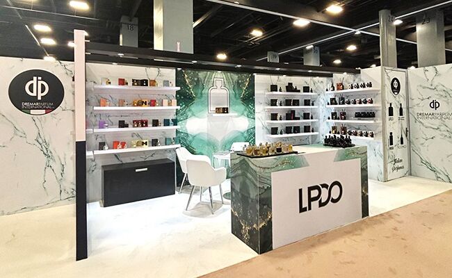 Dremar Parfum completed booth: a corner back wall surrounding a glass display table and product shelves
