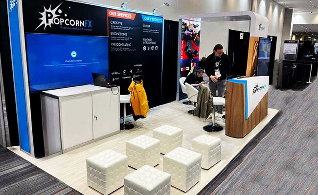 Popcorn FX completed booth: a corner graphic wall with a reception counter, low tables and cube stools