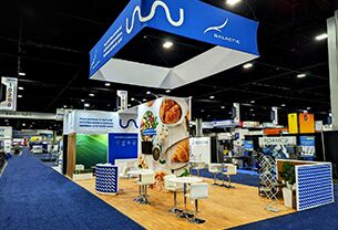 Galactic completed booth: a rectangular hanging sign above food-product graphics and a meeting area