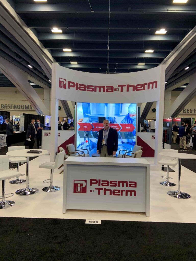 Plasma Therm completed booth: a framed display tower with a central screen and reception counter