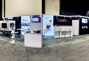 Laserax completed booth: a screen in the back wall above display counters and meeting tables
