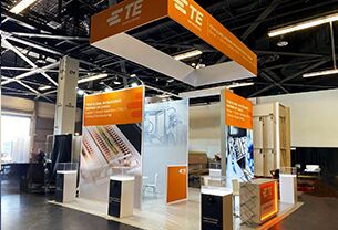 TE CONNECTIVITY completed booth: a rectangular hanging sign above a tall central product-display tower