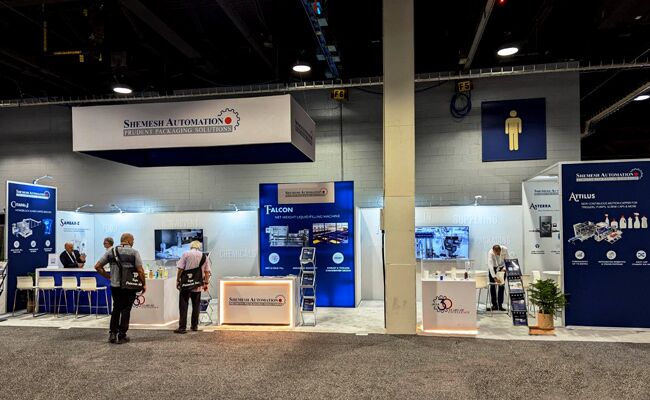 Shemesh Automation completed booth: a rectangular hanging sign above a central display wall and equipment stations