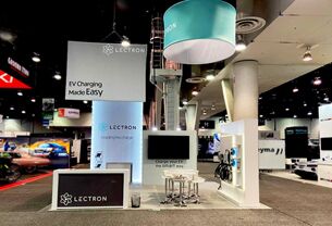 Lectron completed booth: a circular hanging sign above a tall central tower and reception counter