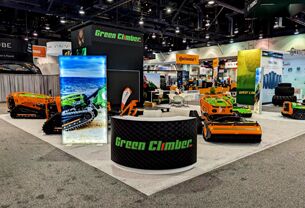 Green Climber completed booth: a circular hanging sign above an open floor displaying compact tracked machines