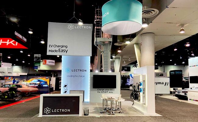 Lectron completed booth: a circular hanging sign above a tall central tower and reception counter