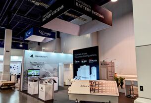 Xerotech completed booth: a suspended rectangular sign above demonstration counters and a video wall