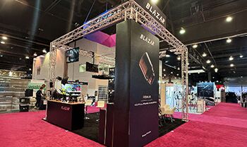 Blazar Lens completed booth: a tall central display tower beneath a suspended rectangular sign