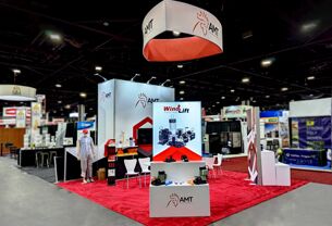AMT completed booth: a circular hanging sign above product displays and reception counters