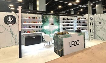 Dremar Parfum completed booth: a corner back wall surrounding a glass display table and product shelves