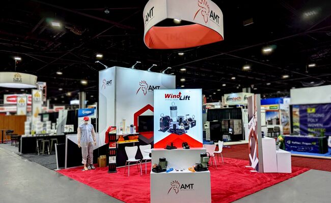 AMT completed booth: a circular hanging sign above product displays and reception counters