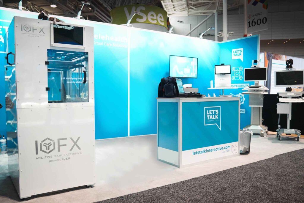 Let’s Talk Interactive completed booth: a screen in a broad display wall behind an angular reception counter