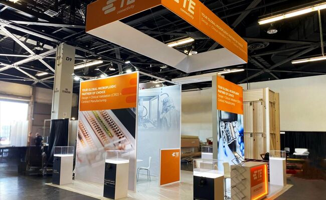 TE CONNECTIVITY completed booth: a rectangular hanging sign above a tall central product-display tower