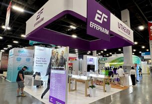 Effepharm completed booth: a suspended box sign over a central tower and freestanding product stations
