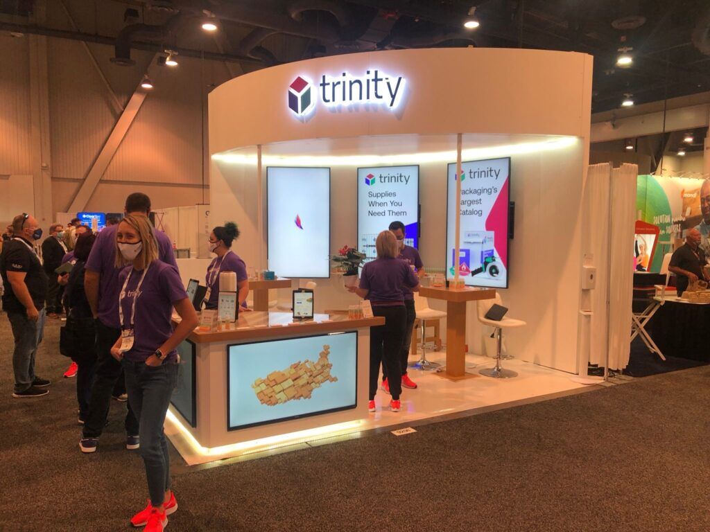Trinity completed booth: a compact display wall with graphic panels, a reception counter and stools