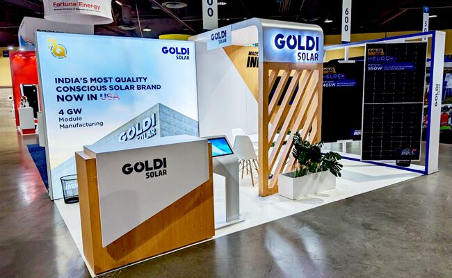 Goldi Solar completed booth: an angled graphic wall beside a solar-panel display and reception counter